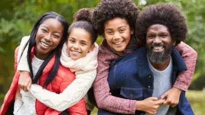 Foster parents being hugged from behind by foster children