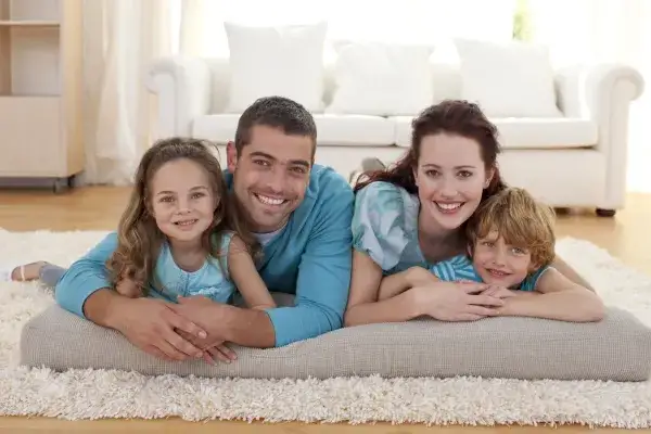 Foster family snuggling with two kids on a rug