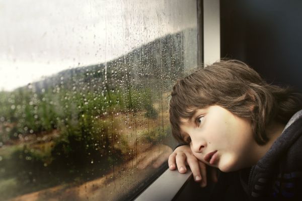 Young child gazing out the window; possibly exhibiting signs of child abuse or neglect