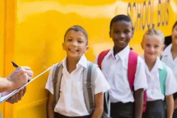 Foster children attending school standing by a school bus