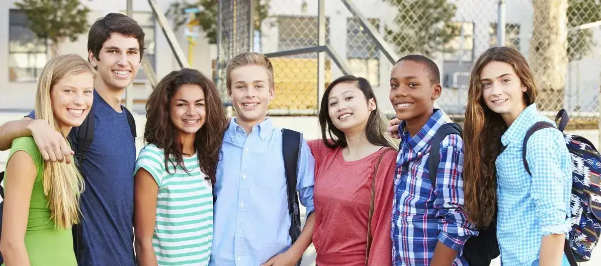 Seven mixed teens standing arm in arm in a row facing the camera