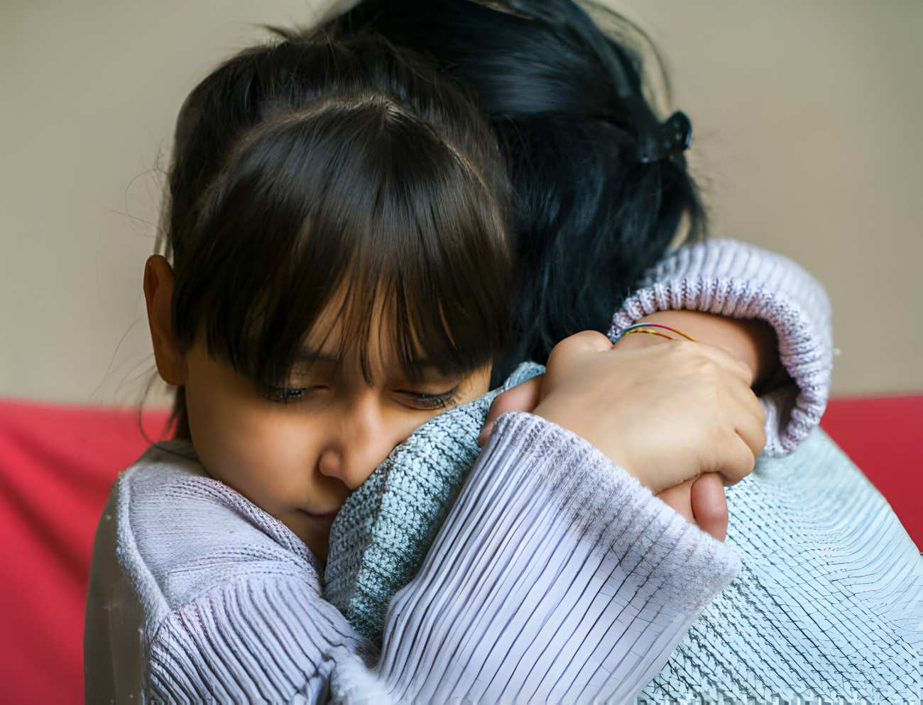 Foster-to-Adopt mom hugs and consoles a young girl, hugging with head on Mom's shoulder