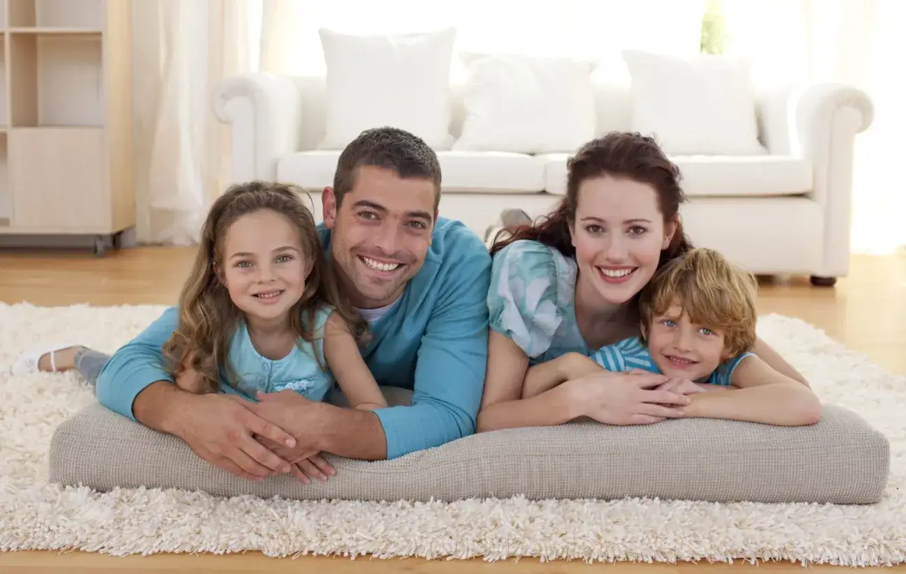 Foster family snuggling with two kids on a rug